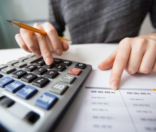 Closeup of accountant counting on calculator and working with table